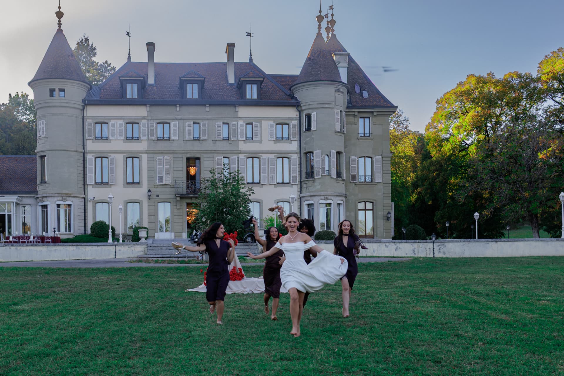 La mariée et ses témoins courant pieds nus sur la pelouse du domaine, le Château de Crassy en toile de fond