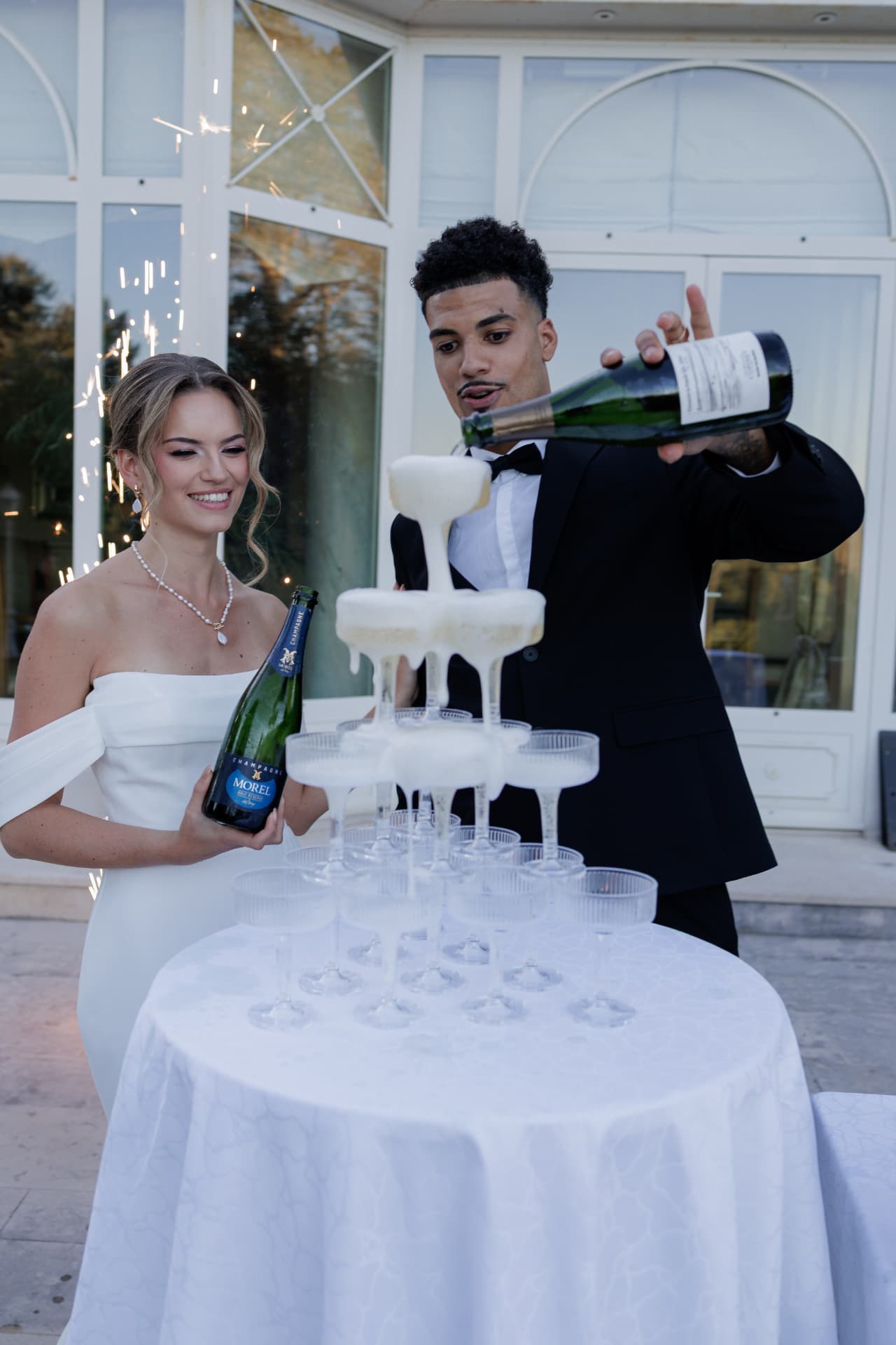 Les mariés font couler une cascade de champagne devant la verrière du Château de Crassy